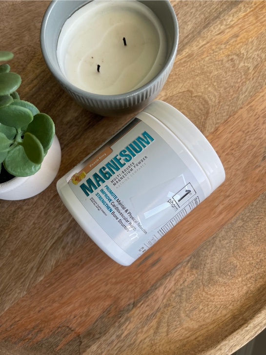 A candle and plant next to 1st phorm magnesium powder